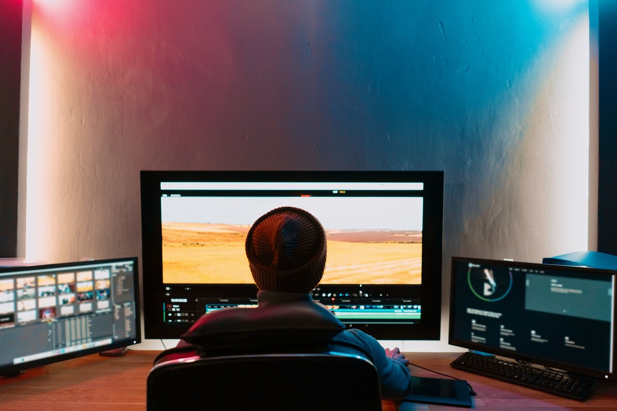 Attractive Male Video Editor Works with Footage or Video on His Personal Computer, he Works in Creative Office Studio or home. Neon lights