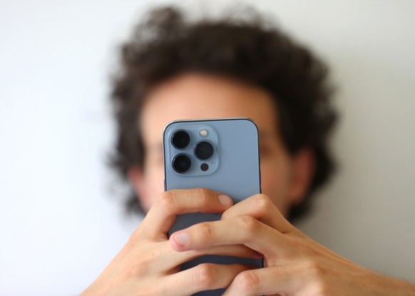 ARCHIV - 06.07.2022, Bayern, Augsburg: Een jonge man tipt een smartphone met een WhatsApp Nachricht. (zu dpa: “Mann aus Potsdam auf WhatsApp um Tausende Euro betrogen”) Foto: Karl-Josef Hildenbr ...