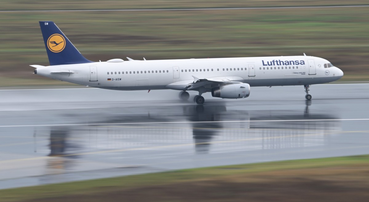 01.08.2024, Hessen, Frankfurt/Main: Ein Airbus 321-200 der Lufthansa startet bei regennasser Startbahn am Frankfurter Flughafen (Aufnahme mit l