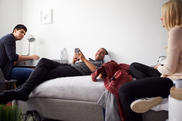 Group Of College Students In Shared House Bedroom Studying Together