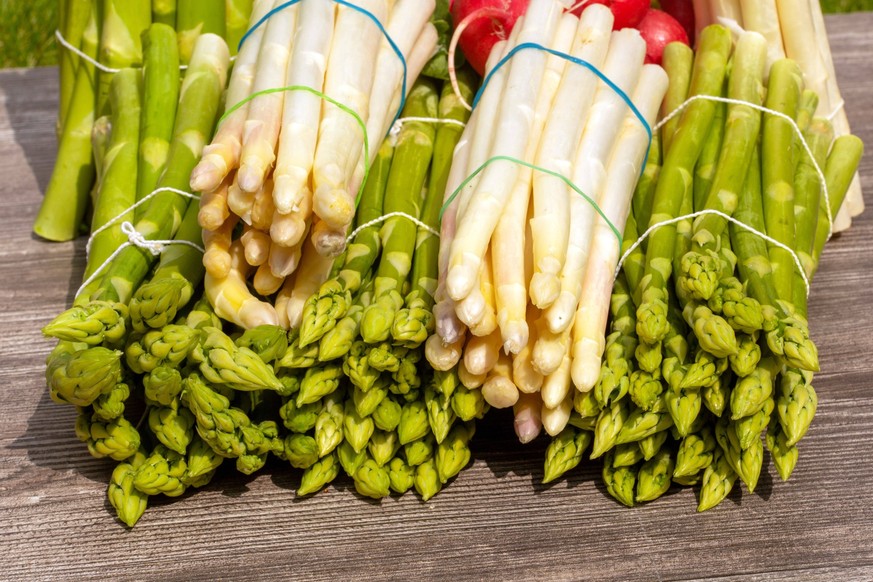 Grüne Spargel und weiße Spargel dekoriert auf einem rustikalen Holztisch *** Green asparagus and white asparagus decorated on a rustic wooden table Copyright: xx