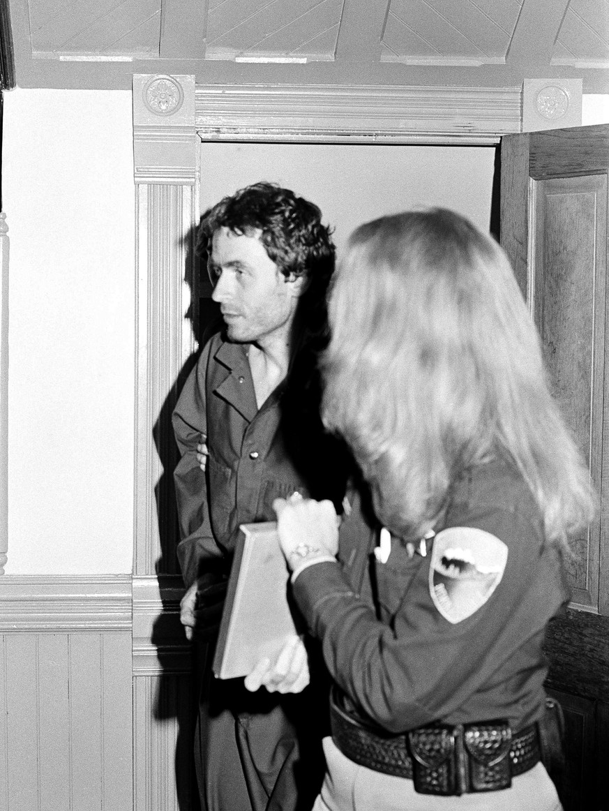 Suspected serial killer Ted Bundy, left, looking disheveled after six days on the run, is escorted by police at Glenwood Springs, Colo., June 13, 1977. Bundy, acting as his own attorney, escaped from  ...