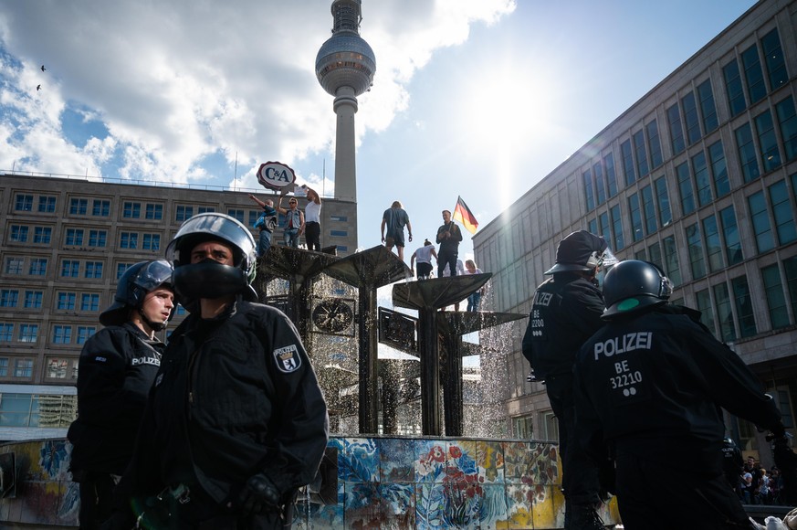 Demonstranten haben bei einer Demo am Samstag am Alexanderplatz in Berlin einen Brunnen erklommen.