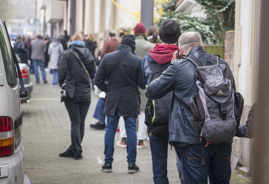 Menschen warten in einer langen Schlange auf dem Gehweg am Corona-Testcenter des Ärztlichen Bereitschaftsdienstes Hessen.