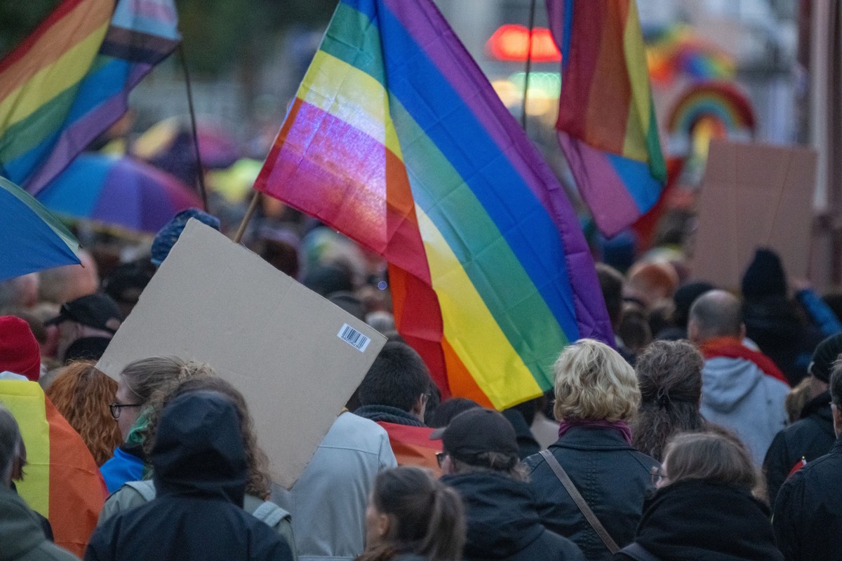 17.10.2024, Mecklenburg-Vorpommern, Neubrandenburg: Teilhnehmer einer Demonstration halten Regenbogenfahnen hoch. In Neubrandenburg haben nach Schätzung der Polizei am Abend etwa 1.000 Menschen gegen  ...