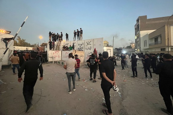 20.07.2023, Irak, Bagdad: Demonstranten erklimmen eine Mauer an der schwedischen Botschaft. Nach Ankündigung einer weiteren geplanten Koranverbrennung in Schweden haben Demonstranten die Botschaft des ...