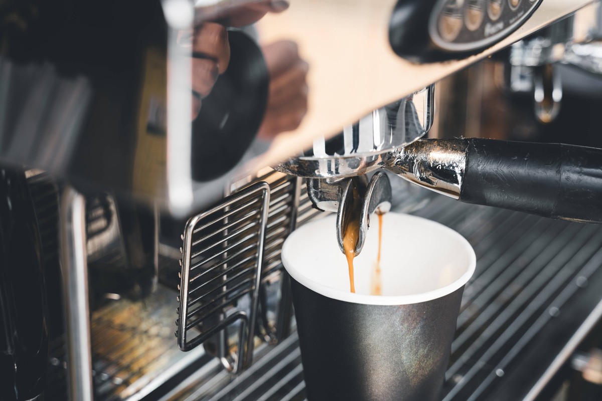 17 July 2023: Freshly brewed coffee flows from a portafilter coffee machine into a To Go cup *** Frisch gebr