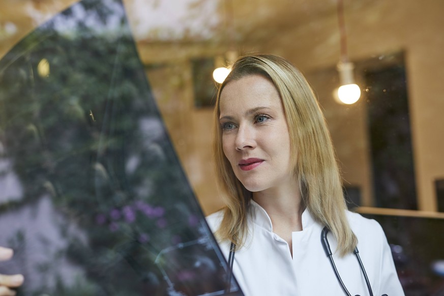 Female doctor looking at x-ray image behind windowpane model released Symbolfoto PUBLICATIONxINxGERxSUIxAUTxHUNxONLY PNEF00980