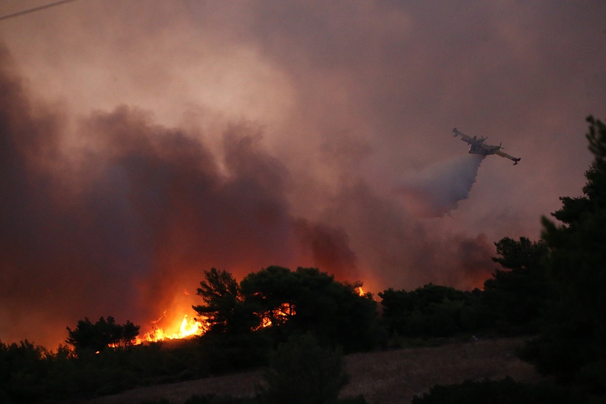 11.08.2024, Griechenland, -: Ein Löschflugzeug wirft während eines großen Brandes nördlich von Athen Wasser ab. Die Bewohner flohen am Sonntag aus ihren Häusern, als ein sich schnell ausbreitender Wal ...