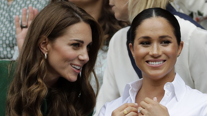 FILE - In this Saturday, July 13, 2019, file photo, Kate, Duchess of Cambridge, left, and Meghan, Duchess of Sussex chat as they sit in the Royal Box on Centre Court to watch the women&#039;s singles  ...