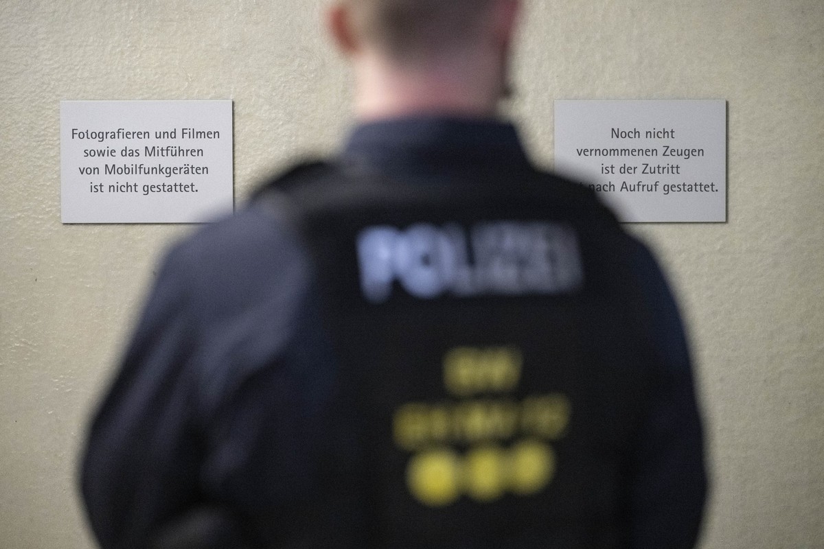 15.09.2025, Baden-Württemberg, Mannheim: Ein Polizeibeamter steht beim Auftakt im Prozess gegen drei junge, mutmaßliche IS-Sympathisanten vor einer Tür zu einem Saal des Landgerichts Mannheim.Den bei ...