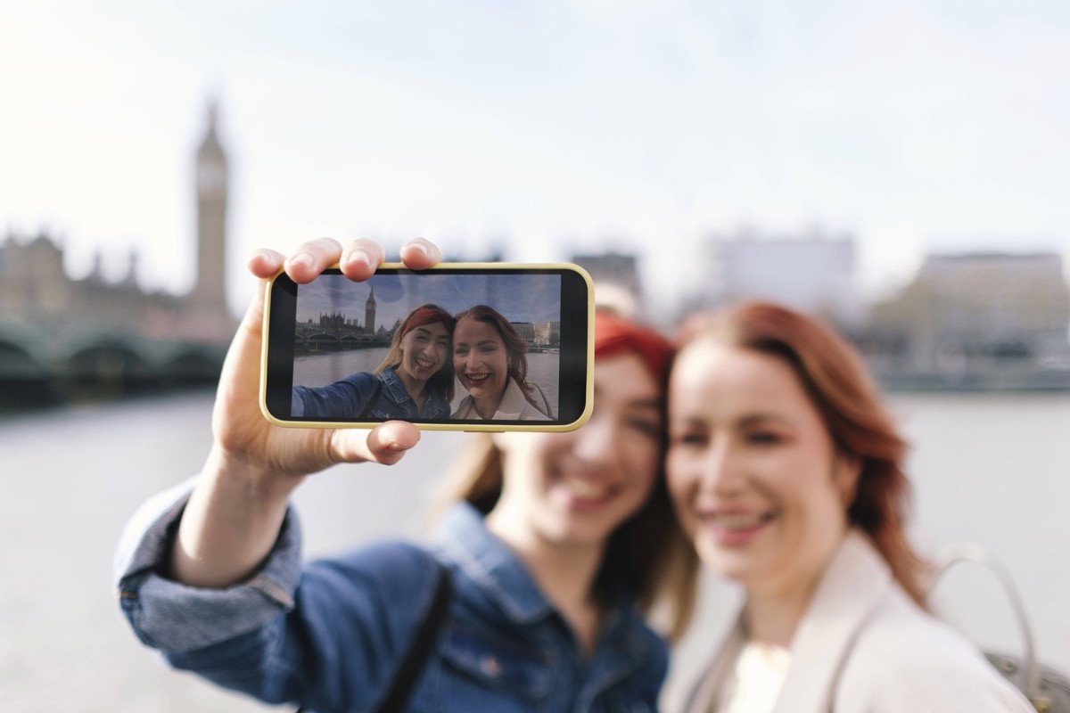Smiling friends taking selfie through smart phone in city of London model released, Symbolfoto property released, ASGF05003