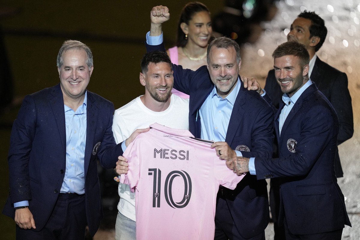 Inter Miami's Lionel Messi, center left, holds his new Inter Miami team jersey as he poses with team co-owners Jorge Mas, left, Jose Mas, second right, and David Beckham during a celebration by t ...