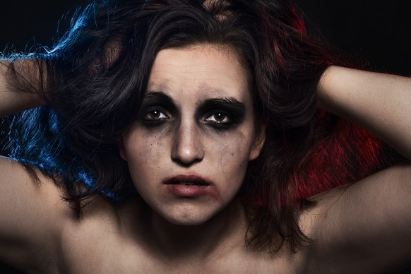 scared woman with smeared cosmetics on dark background