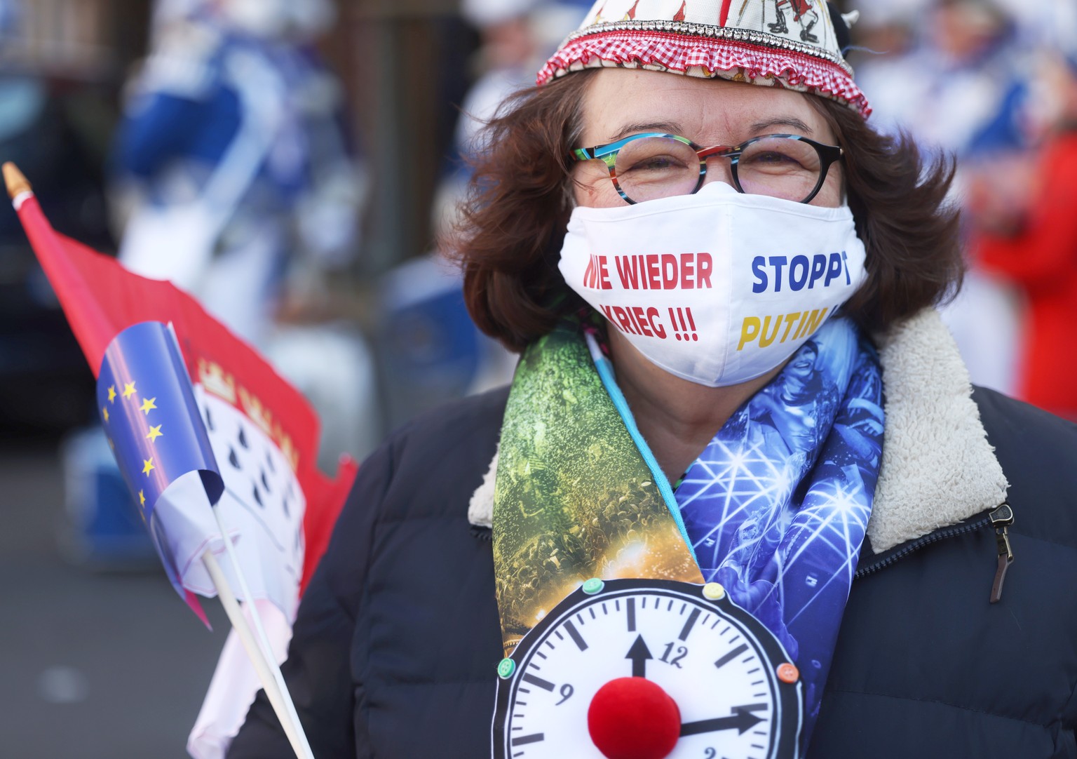 28.02.2022, Nordrhein-Westfalen, K�ln: Eine Karnevalistin tr�gt bei der Friedensdemonstration am Rosenmontag eine Schutzmaske mit der Aufschrift &quot;Nie wieder Krieg !!! Stoppt Putin !!!&quot;. Nach ...