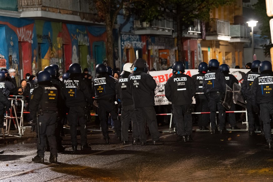 09.10.2020, Berlin: Polizisten stehen in der Rigaer Straße vor Demonstranten, die gegen die Räumung des besetzten Hauses «Liebig 34» protestieren. Das Haus Liebigstraße 34 soll ab 7.00 Uhr geräumt wer ...