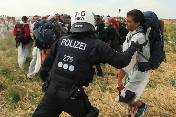 Ein Polizist versucht, einen Aktivisten am Betreten des Tagebau Garzweiler zu hindern.