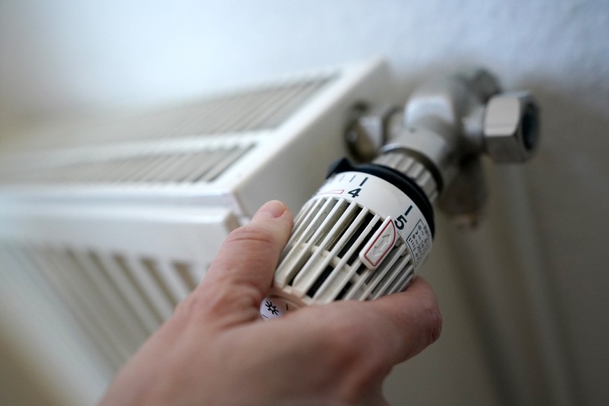 ARCHIV - 09.03.2022, Hamburg: Eine Frau dreht an einem Heizungsthermostat. Das Heizungsgesetz wird es nun doch nicht vor der Sommerpause durch den Bundestag schaffen. Das Bundesverfassungsgericht hat  ...