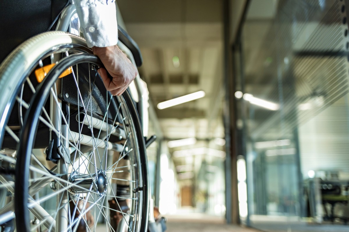 Close-up Of one unrecognizable Businessman Sitting On Wheelchair In Office during the day.