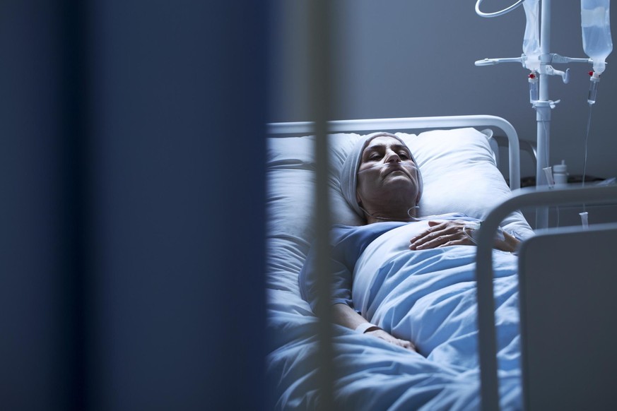 Lonely young woman suffering from cancer while lying in hospital bed
