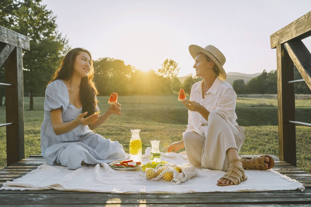 Happy women holding slices of watermelon sitting on picnic blanket model released, Symbolfoto, NDEF00391