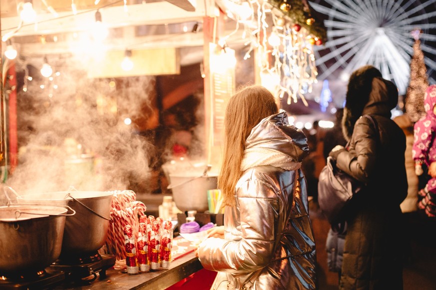 Young woman standing by food court at Christmas market in city