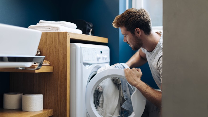 Young man doing the laundry at home model released Symbolfoto property released PUBLICATIONxINxGERxSUIxAUTxHUNxONLY SODF00707