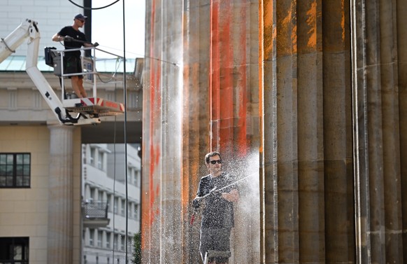 18.09.2023, Berlin: Reinigungsarbeiten nach einem Farbanschlag der so genannten letzten Generation auf das Brandenburger Tor. Foto: Britta Pedersen/dpa +++ dpa-Bildfunk +++