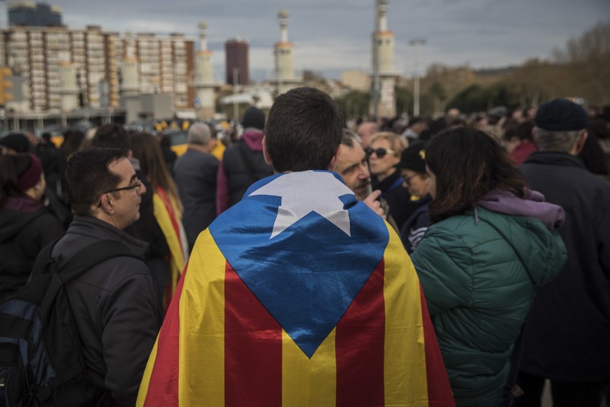 People, one of them wrapped in a Catalan independence flag, gather during a protest in support of Catalonian politicians jailed on charges of sedition and condemning the arrest of Catalonia&#039;s for ...