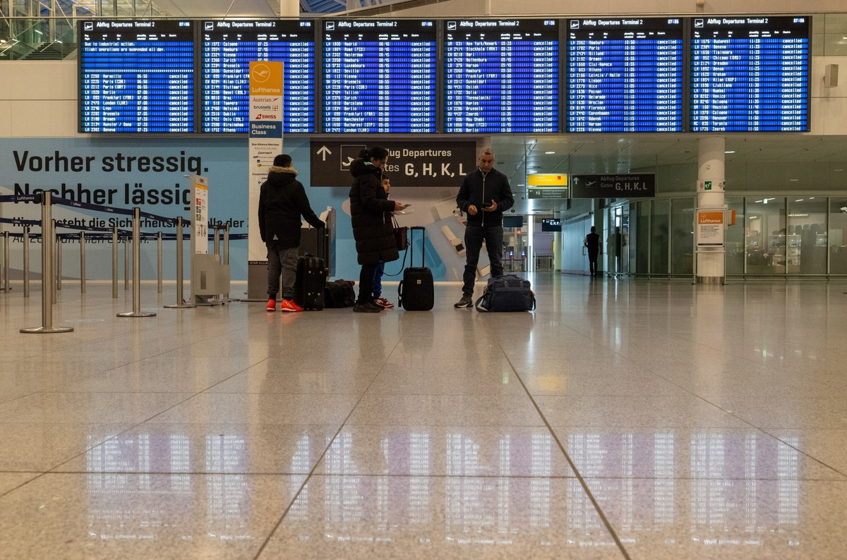 17.02.2023, Bayern, München: Gestrandete Passagiere stehen am Flughafen München vor einer Anzeigetafel, auf der alle Flüge annuliert sind. Der Airport soll im Rahmen eines Streiks der Gewerkschaft ver ...