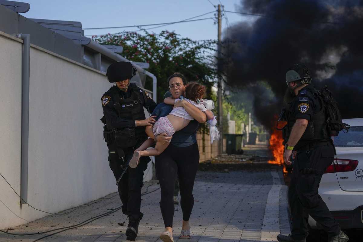 07.10.2023, Israel, Ashkelon: Israelische Polizei evakuieren eine Frau und ein Kind von einem Ort, der von einer aus dem Gazastreifen abgefeuerten Rakete getroffen wurde. Nach massiven Angriffen aus d ...