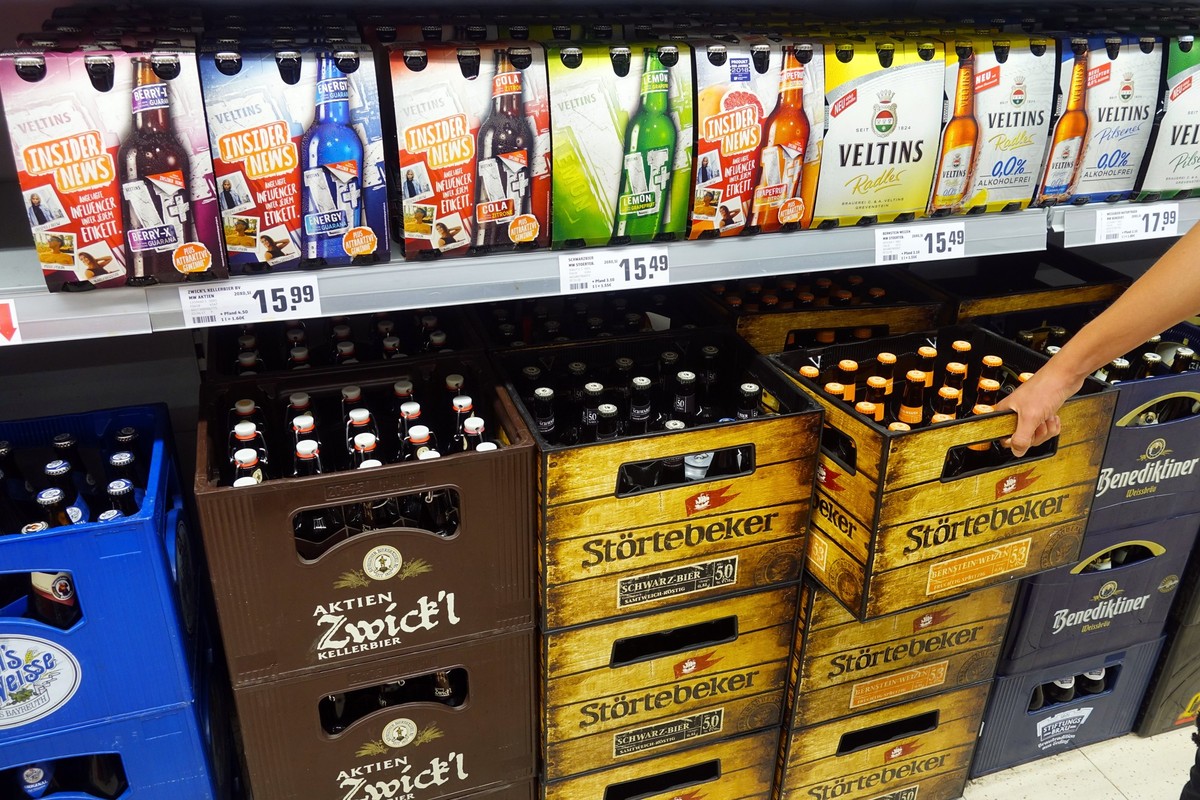 GERMANY - AUGUST 2018: Beer and Shandies in a shop. Shopper selecting beer of an assortment german brand beer crates and sixpacks in a REWE supermarket.