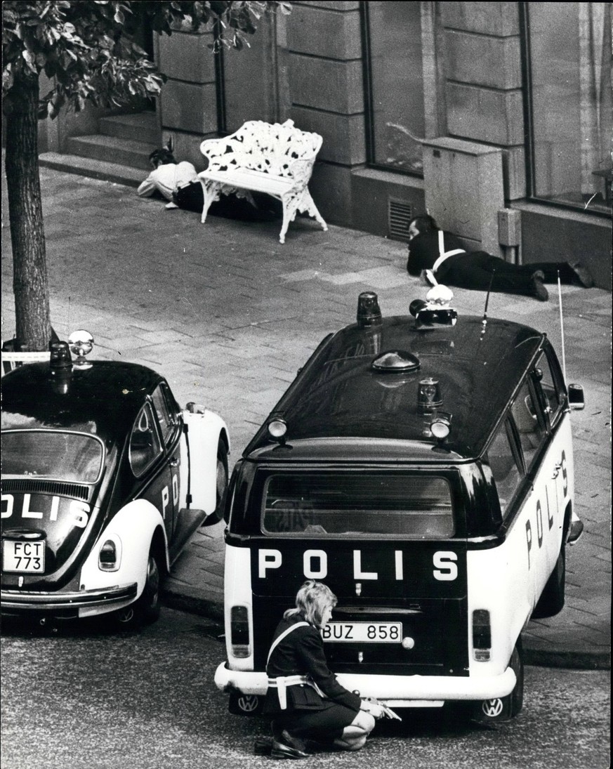 Aug. 08, 1973 - Gunman Holds hostages In Stockholm Bank. A policewoman, gun in hand (foreground), crouches behind a police van, outside the bank in Stockholm where a gunman is holding four hostages. T ...