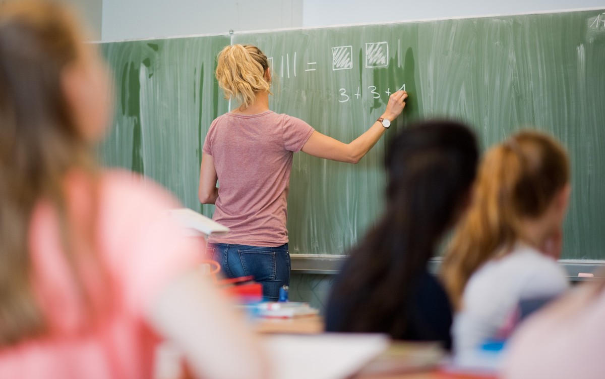 ARCHIV - 09.06.2022, Niedersachsen, Hannover: Eine junge Lehrerin schreibt an eine Schultafel im Mathematikunterricht an einer Integrierten Gesamtschule.

Lehrerinnen und Lehrer stehen nicht nur im Kl ...