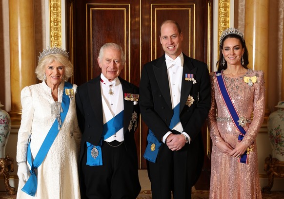 ARCHIV - 05.12.2023, Großbritannien, London: Königin Camilla (l-r), König Charles III. aus Großbritannien, sowie William, Prinz von Wales, und Kate, Prinzessin von Wales, stehen für ein Foto vor dem d ...