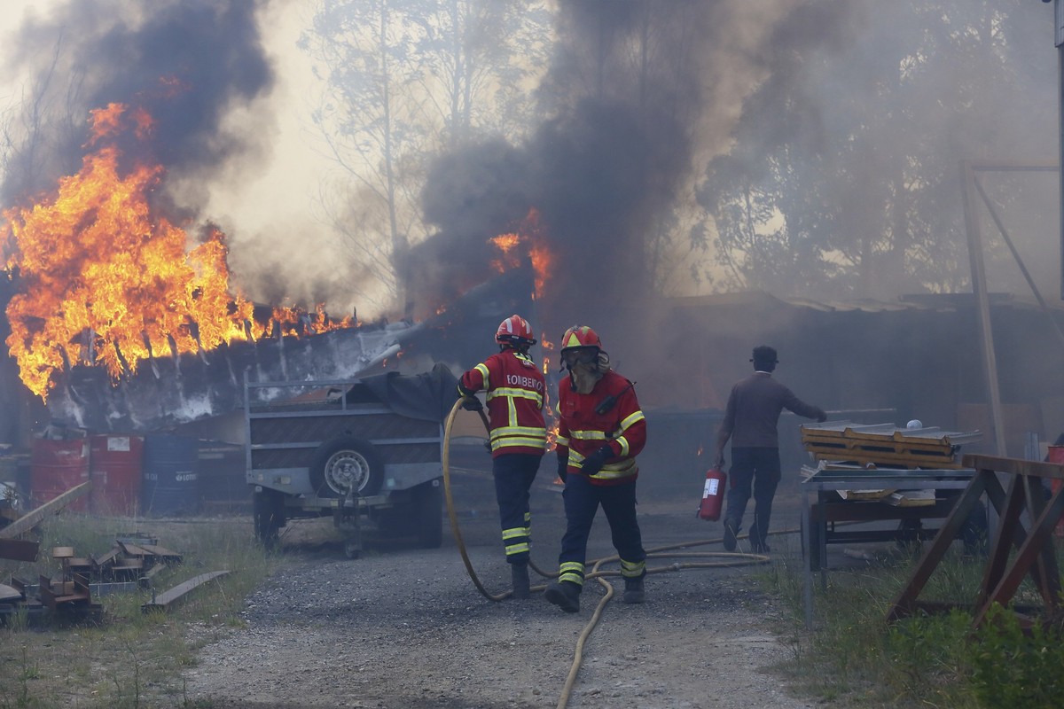 dpatopbilder - 16.09.2024, Portugal, Sever do Vouga: Feuerwehrleute sind während eines Brandes in einem metallverarbeitenden Lagerhaus im Einsatz. Die Stadt im Norden des Landes ist von Waldbränden um ...