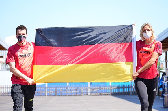 Wasserspringer Patrick Hausding (l) und Beachvolleyballspielerin Laura Ludwig halten eine Deutschlandfahne vor der Pressekonferenz vom Deutschen Olympischen Sportbund (DOSB) zur Vorstellung des Fahnen ...