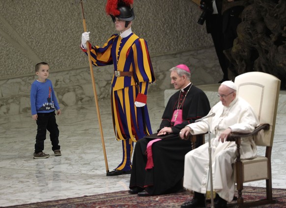 A child approaches a Swiss guard after getting up to the area where Pope Francis is sitting, right, during his weekly general audience in the Paul VI Hall at the Vatican, Wednesday, Nov. 28, 2018. (AP ...