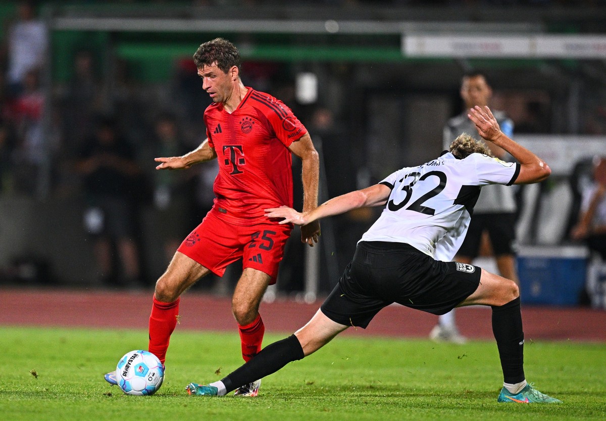 16.08.2024, Baden-Württemberg, Ulm: Fußball, DFB-Pokal, 1. Runde, SSV Ulm 1846 - Bayern München, Donaustadion: Münchens Thomas Müller (l) und Ulms Philipp Strompf. WICHTIGER HINWEIS: Gemäß den Vorgabe ...