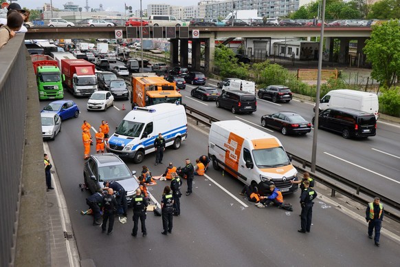 Police officer work to remove glue from the hands of activists of the &quot;Letzte Generation&quot; (Last Generation), who glued themselves to the A100 highway to protest for climate councils, a speed ...