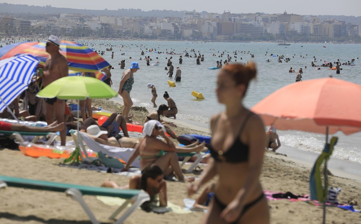 ARCHIV - 18.07.2023, Spanien, Palma de Mallorca: Menschen schwimmen und sonnen sich am Strand von Arenal der Mittelmeer-Insel Mallorca. (zu dpa «Frühe Osterferien bereiten den Mallorca-Hoteliers Sorge ...