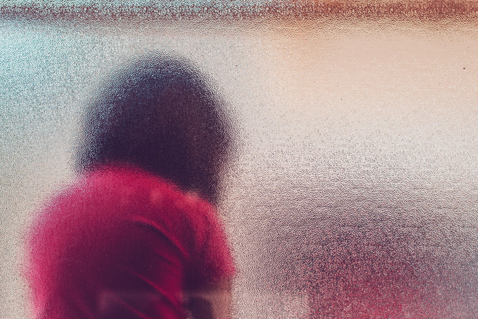 Silhouette of unrecognizable sad autistic girl behind stained glass window sitting alone in the backyard