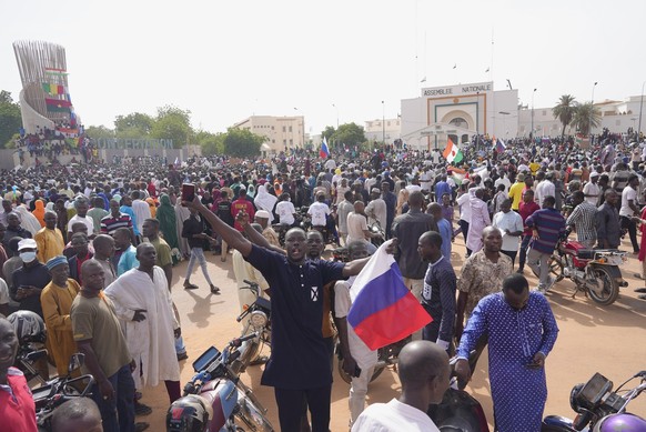 30.07.2023, Niger, Niamey: Ein Mensch hält eine russische Nationalfahne während er an einem Marsch teilnehmen, zu dem Anhänger des Putschisten General Omar Tchiani aufgerufen haben. Tchiani hat sich z ...