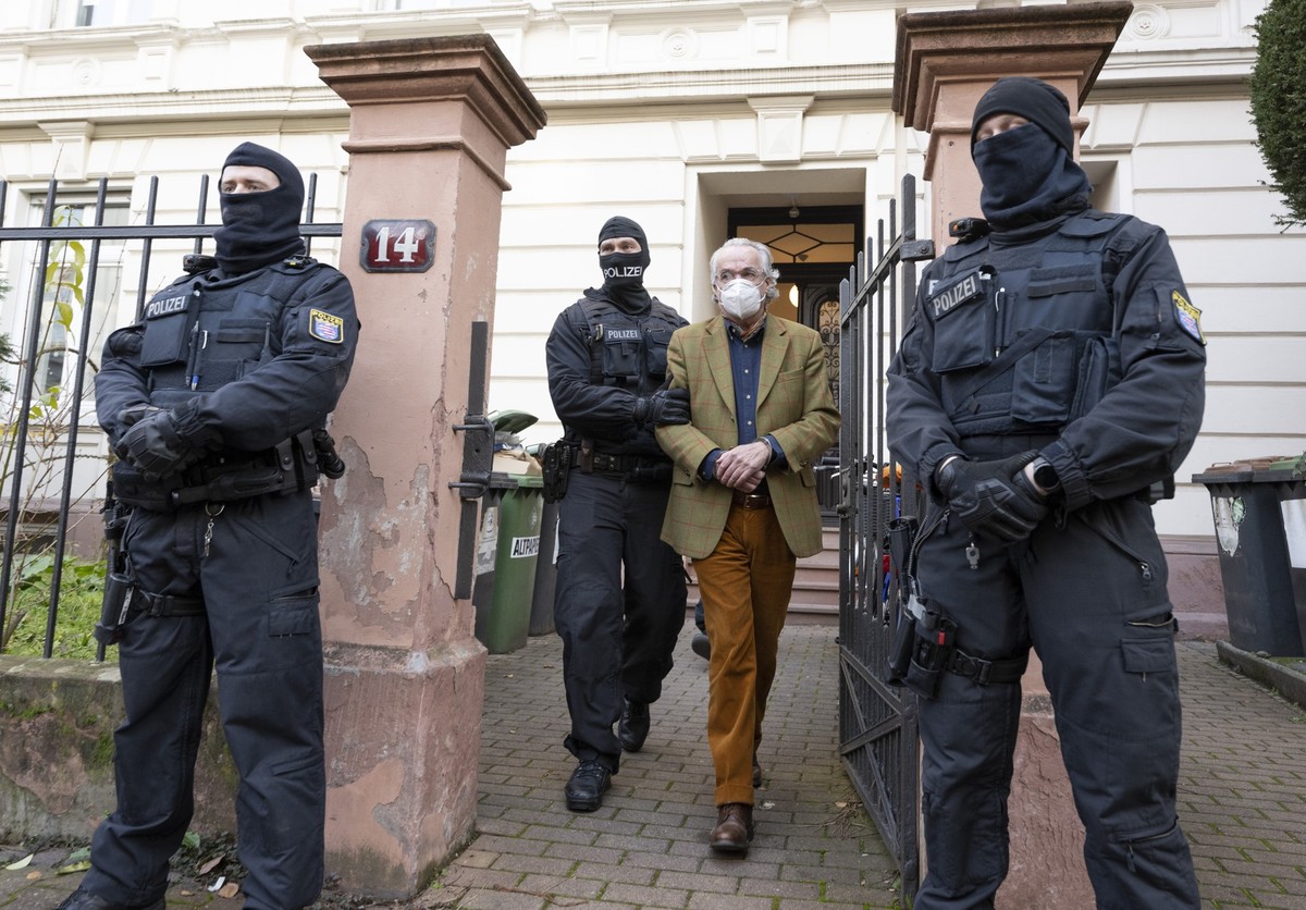 07.12.2022, Hessen, Frankfurt/Main: Bei einer Razzia gegen sogenannte «Reichsbürger» führen vermummte Polizisten, nach der Durchsuchung eines Hauses Heinrich XIII Prinz Reuß (2.v.r.) zu einem Polizeif ...