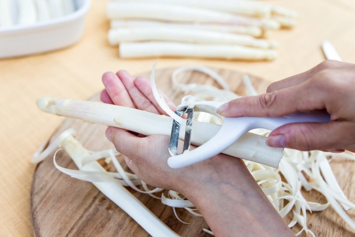 white asparagus on a table, woman is peeling the asparagus, close up