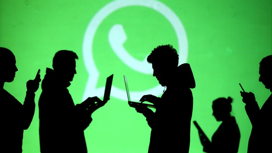 FILE PHOTO: Silhouettes of laptop and mobile device users are seen next to a screen projection of Whatsapp logo in this picture illustration taken March 28, 2018. REUTERS/Dado Ruvic/File Photo