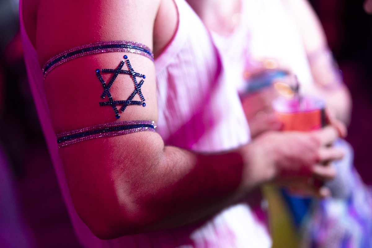 13.05.2025, Schweiz, Basel: Ein Mann tr�gt die israelische Flagge als Schmuck am Arm im ESC-Village der Messe Basel vor dem ersten Halbfinale des 69. Eurovision Song Contest. Foto: Til Buergy/KEYSTONE ...