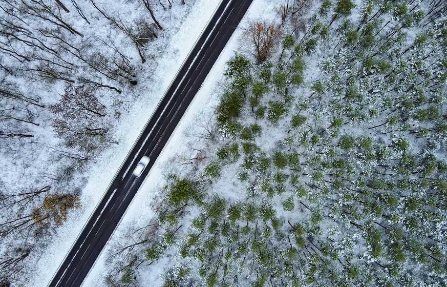 dpatopbilder - 08.12.2022, Brandenburg, Petersdorf: Ein wenig Schnee liegt in einem Wald durch den eine Landstra