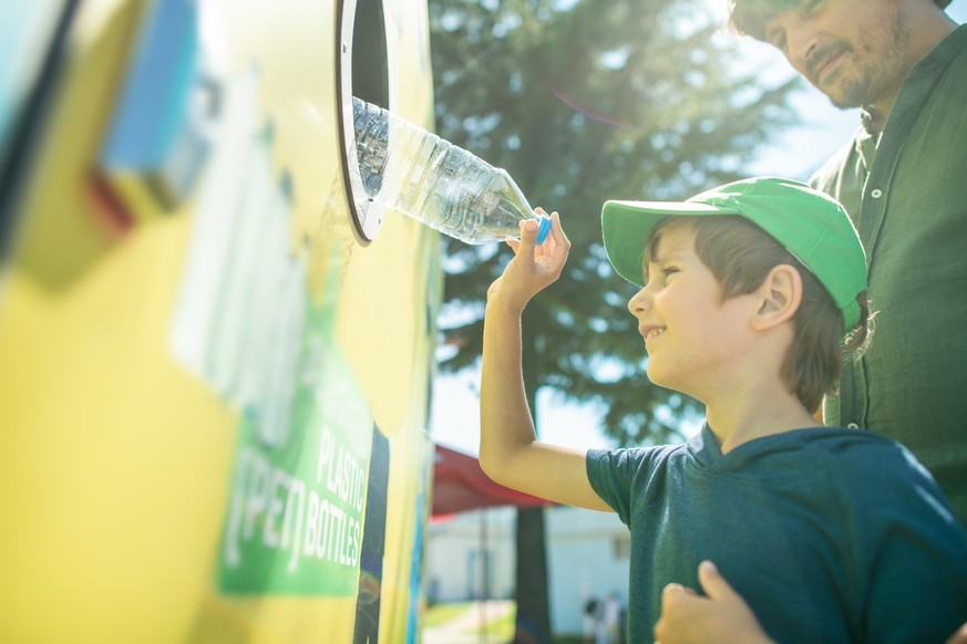 Family trowing plastic bottle in a garbage bin