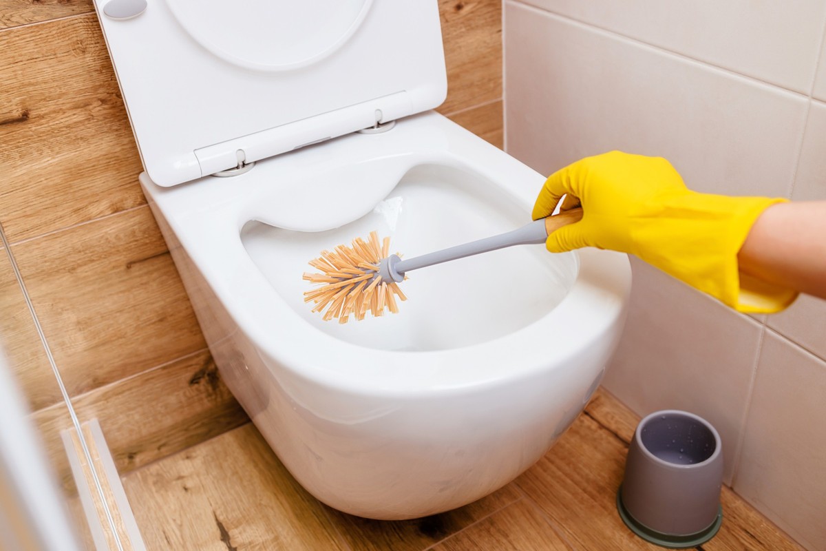 close-up of the bathroom Woman&#039;s hands in rubber yellow gloves with the help of a brush and powder cleans the toilet. The concept of cleaning, hygiene, disinfection. Copy paste for your design.